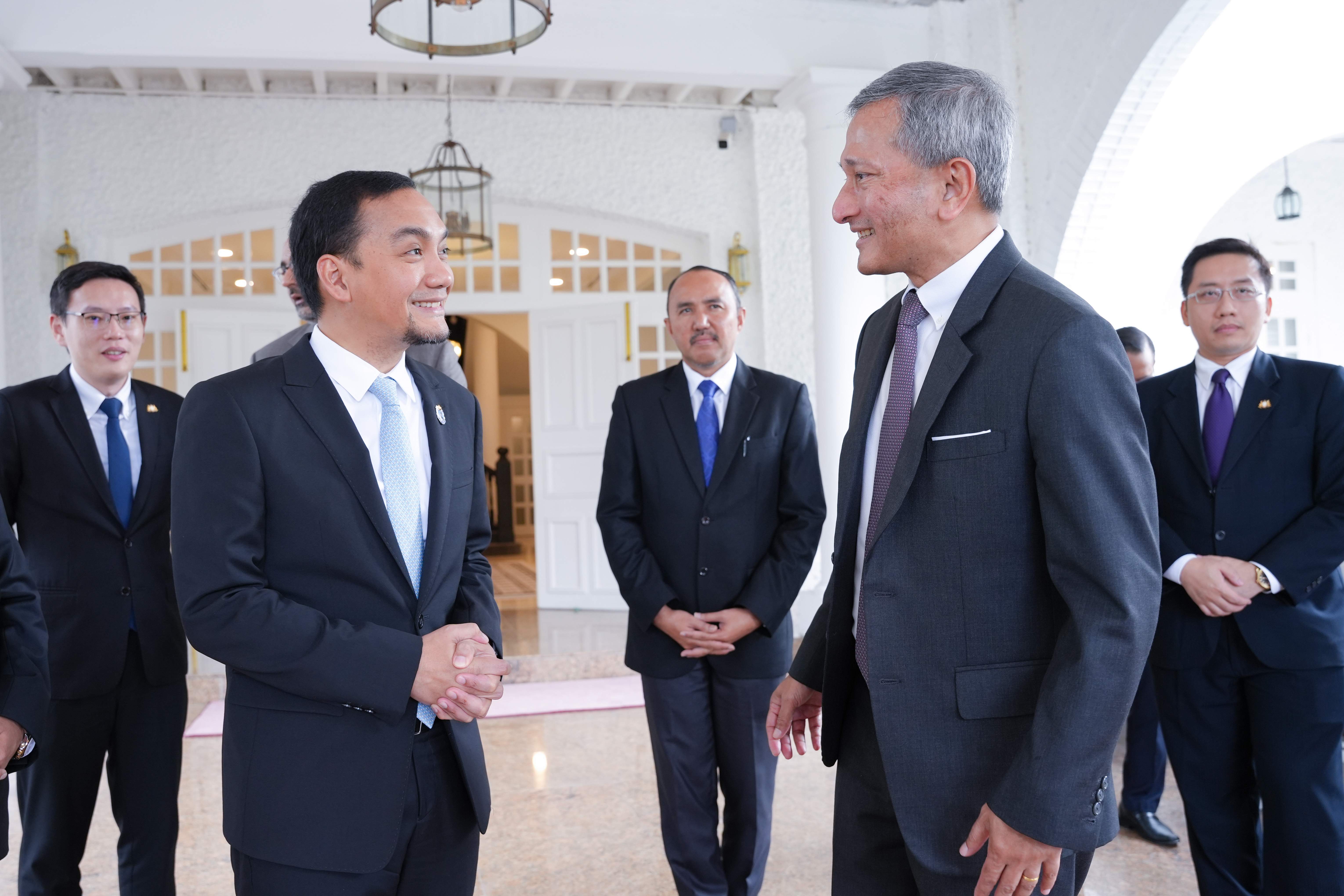 Several men in suits standing in front of a building are conversing.